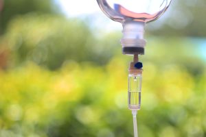 An IV bottle with a green blurred background